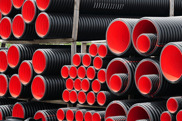 Stacked corrugated black and red pipes, Industrial-grade drainage and conduit pipes